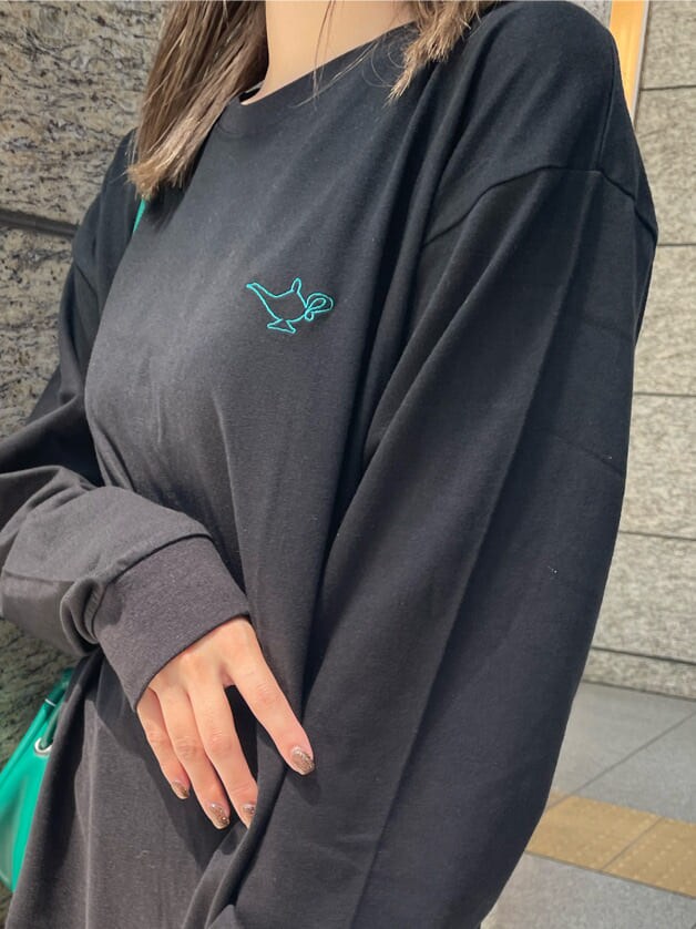 グリーン系のハンドバッグ、ブラック系のブーツ、ブラック系のTシャツ/カットソーを着用したレディースの夏コーディネートの6枚目の写真