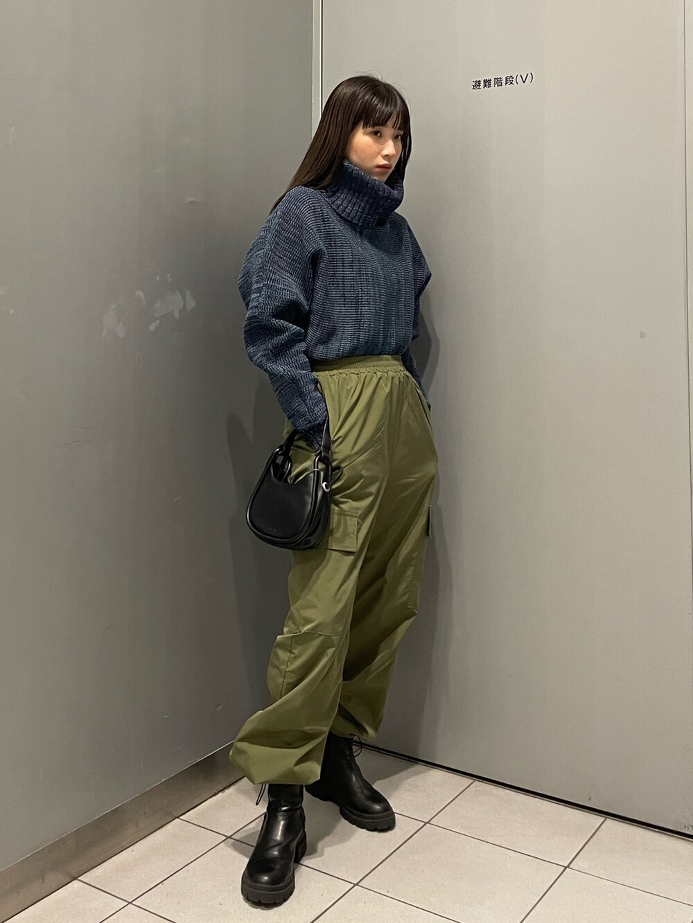 ブルー系のニット/セーター、ブラック系のハンドバッグ、ブラック系のブーツを着用したレディースの秋コーディネートの4枚目の写真