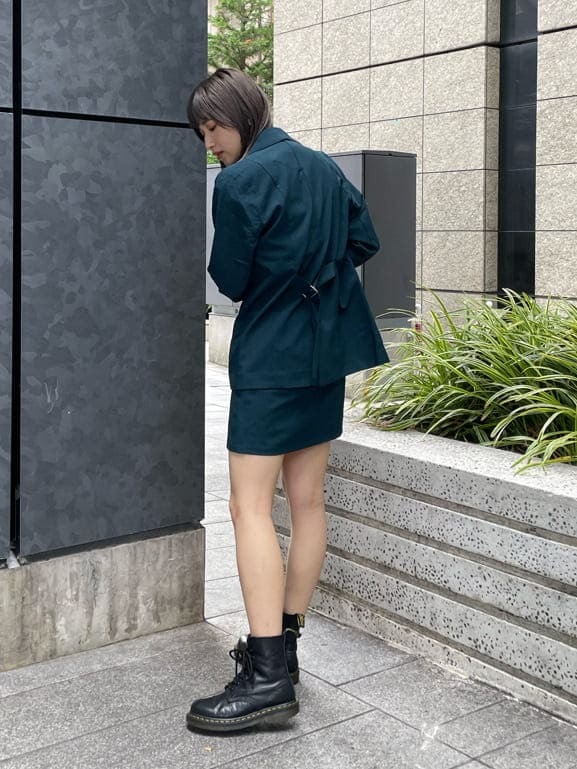 グリーン系のテーラードジャケット、グリーン系のスカート、ブラック系のニット/セーターを着用したレディースの夏コーディネートの3枚目の写真