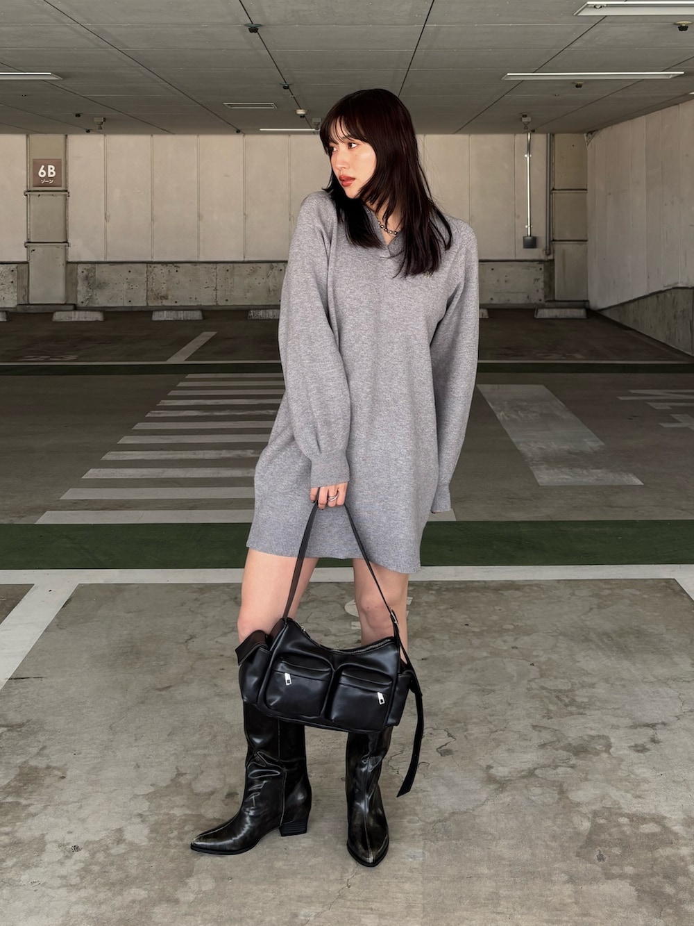 グレー系のワンピース、ブラウン系のブーツ、ブラック系のショルダーバッグを着用したレディースの冬コーディネートの2枚目の写真