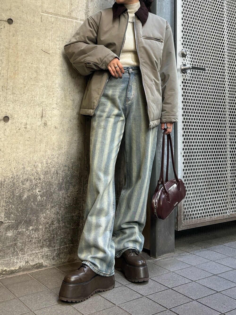 ベージュ系のブルゾン、ブルー系のデニムパンツを着用したレディースの秋コーディネートの2枚目の写真