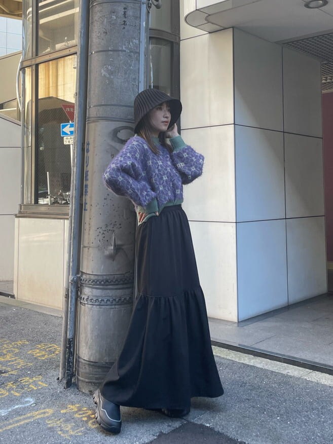 ブラック系のブーツ、ブラック系のスカート、パープル系のニット/セーターを着用したレディースの秋コーディネートの2枚目の写真