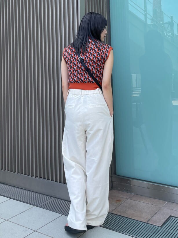 ブラック系のショルダーバッグ、オレンジ系のニット/セーターを着用したレディースの夏コーディネートの5枚目の写真