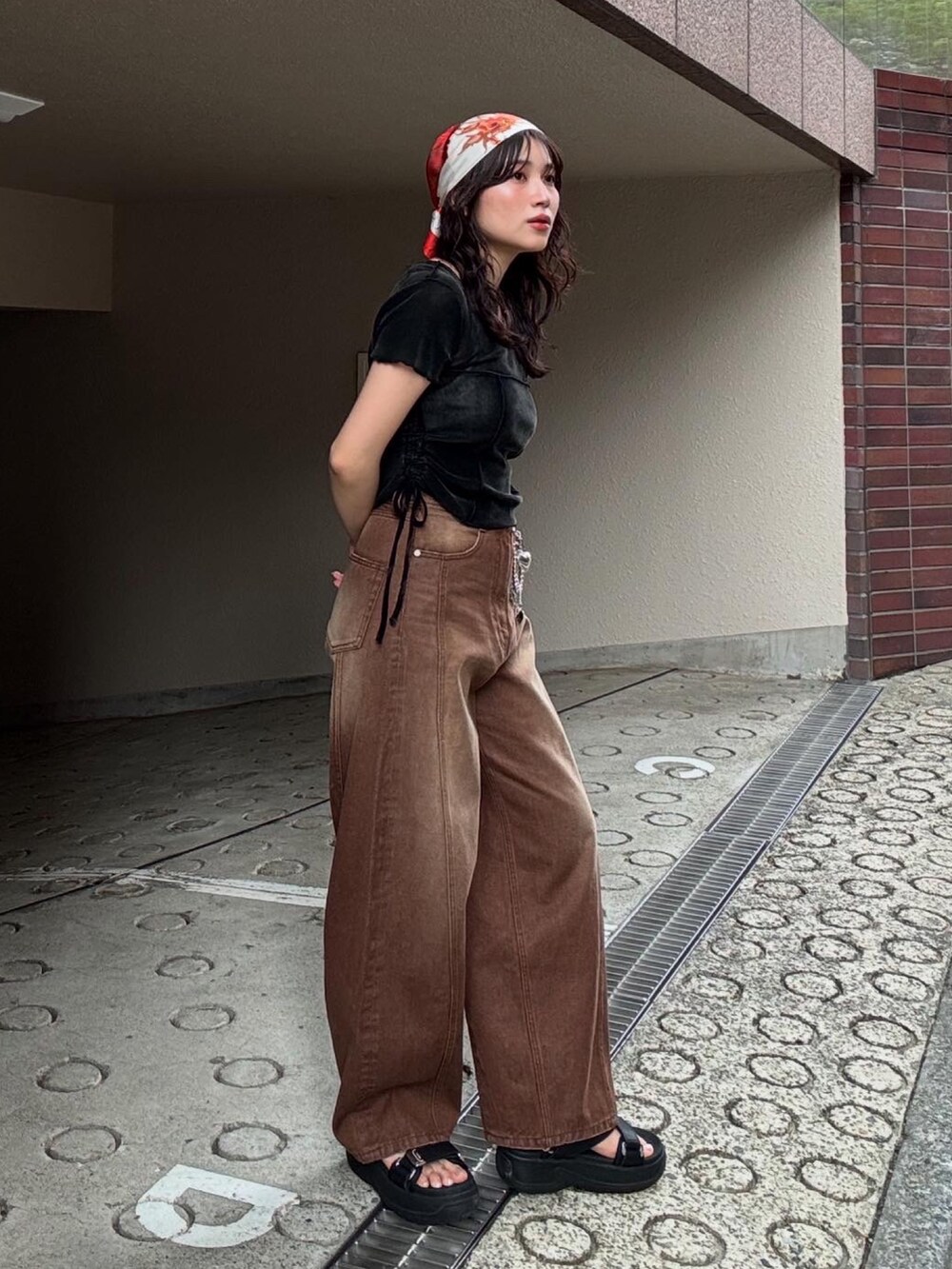 ブラウン系のデニムパンツ、ブラック系のサンダル、オレンジ系のバンダナ/スカーフを着用したレディースの春コーディネートの3枚目の写真