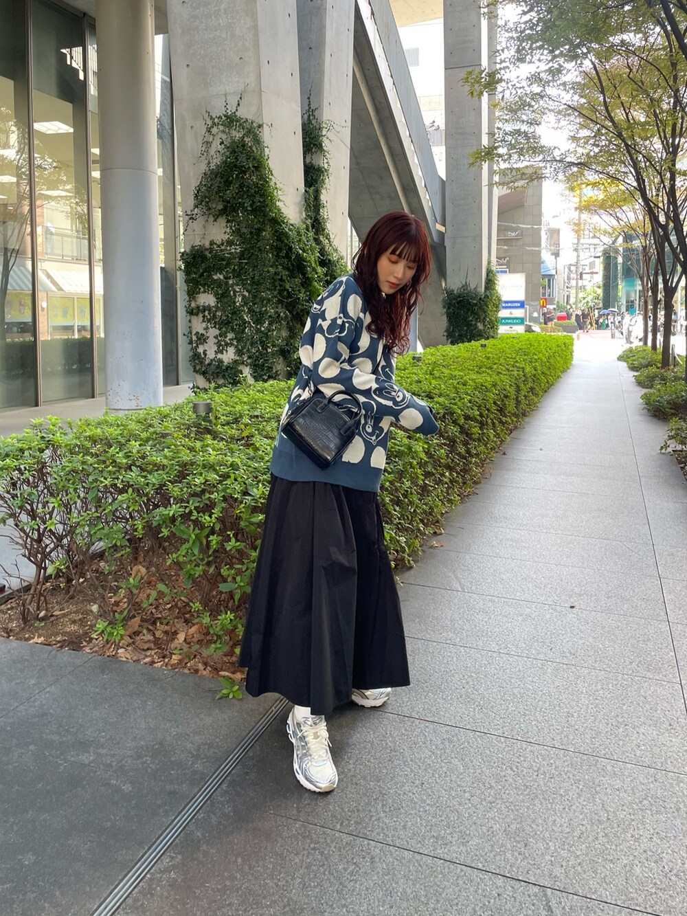 ブルー系のニット/セーター、ブラック系のスカートを着用したレディースの秋コーディネートの2枚目の写真