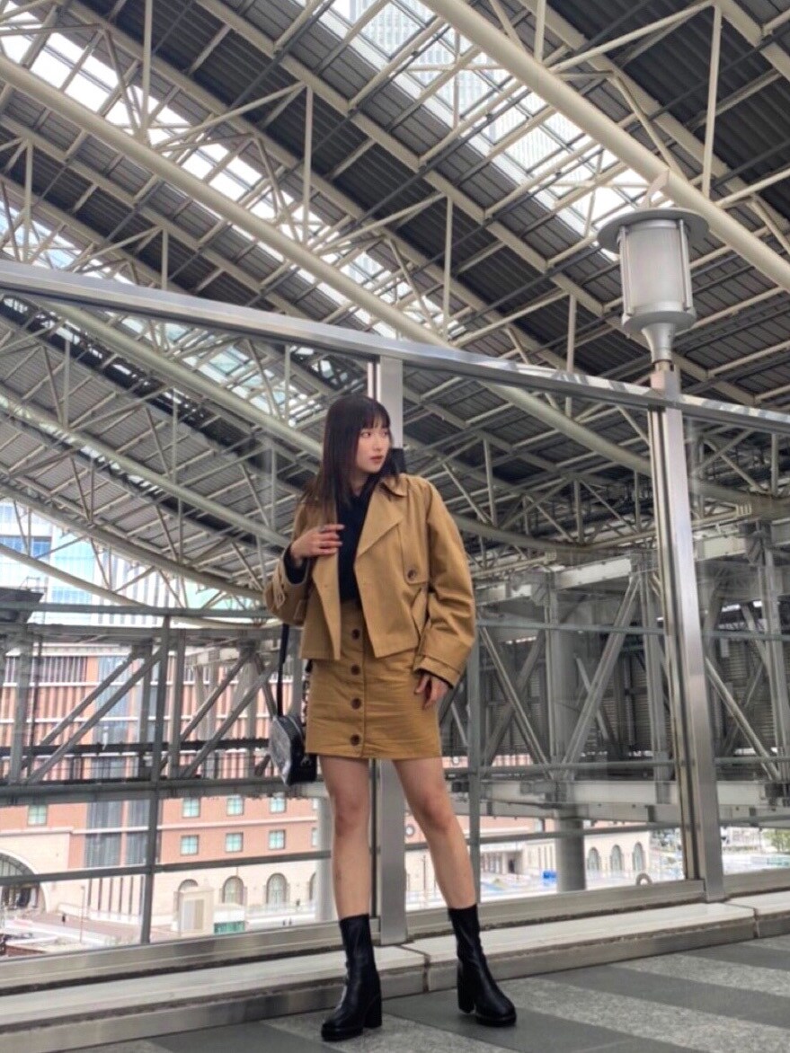 ベージュ系のトレンチコート、ベージュ系のスカート、ブラック系のブーツを着用したレディースの冬コーディネートの4枚目の写真