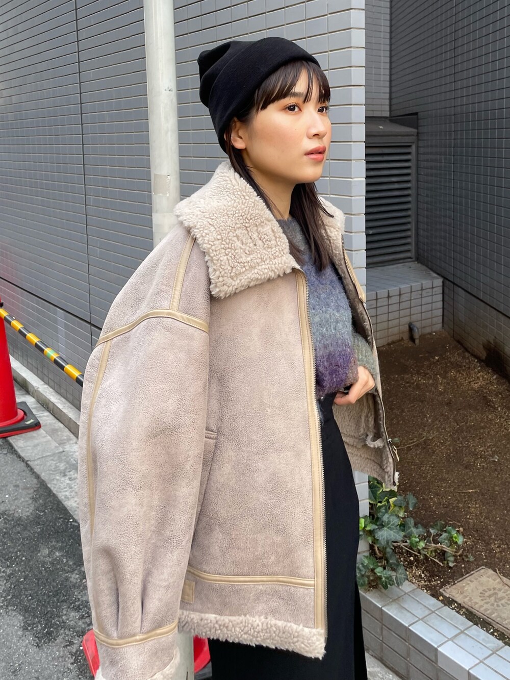 ベージュ系のムートンコート、パープル系のニット/セーター、ブラック系のスカートを着用したレディースの秋コーディネートの4枚目の写真