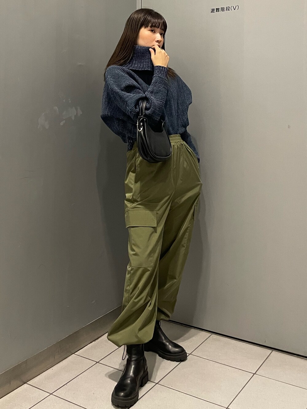 ブルー系のニット/セーター、ブラック系のハンドバッグ、ブラック系のブーツを着用したレディースの秋コーディネートの2枚目の写真