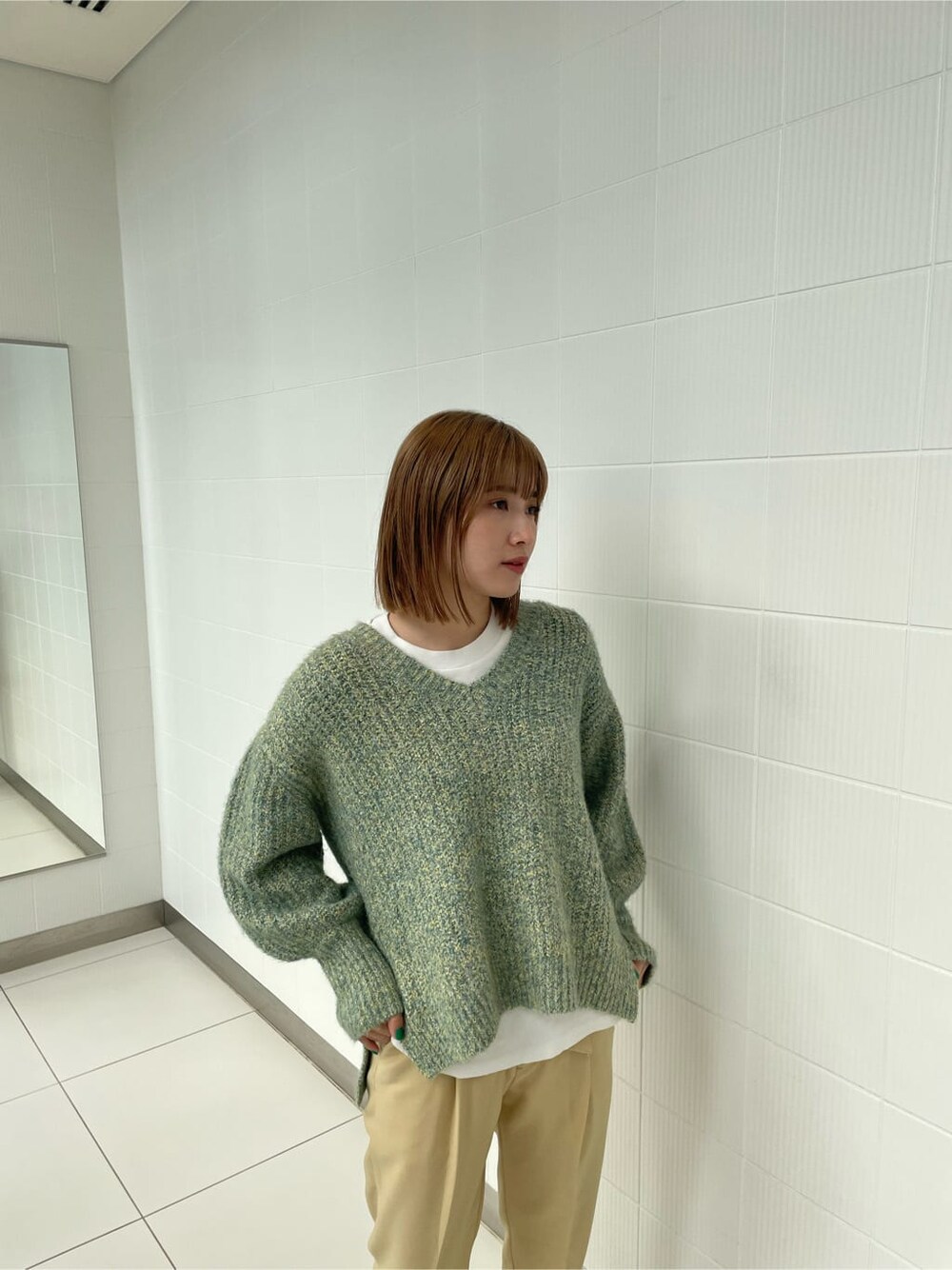 グリーン系のニット/セーター、イエロー系のスラックスを着用したレディースの冬コーディネートの4枚目の写真