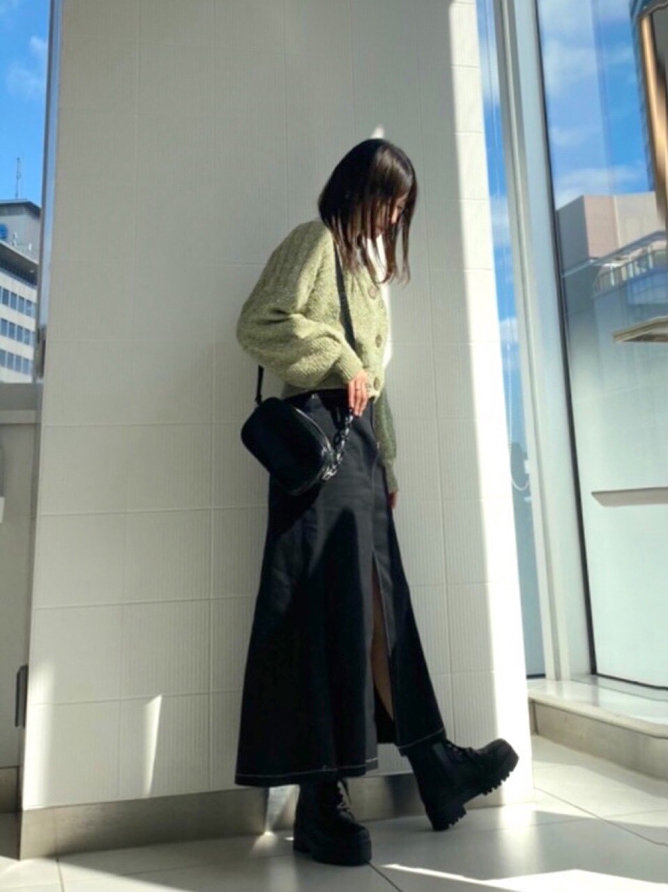 ブラック系のブーツ、ブラック系のスカート、ブラック系のショルダーバッグを着用したレディースの冬コーディネートの2枚目の写真