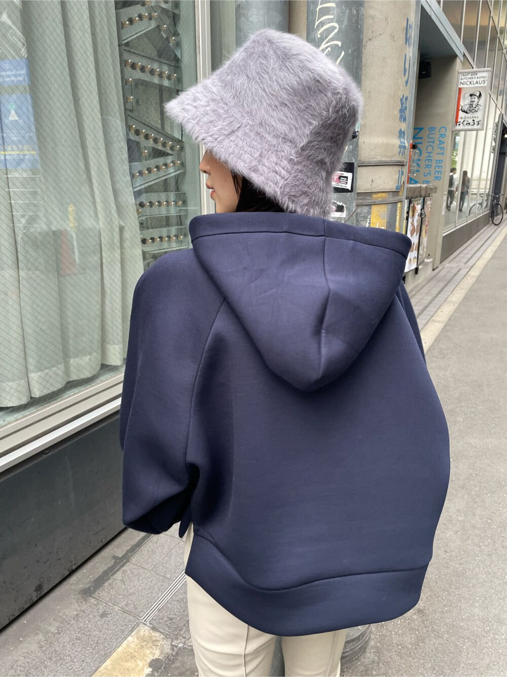 ホワイト系のスラックス、ブラック系のブーツ、ブルー系のパーカーを着用したレディースの秋コーディネートの5枚目の写真