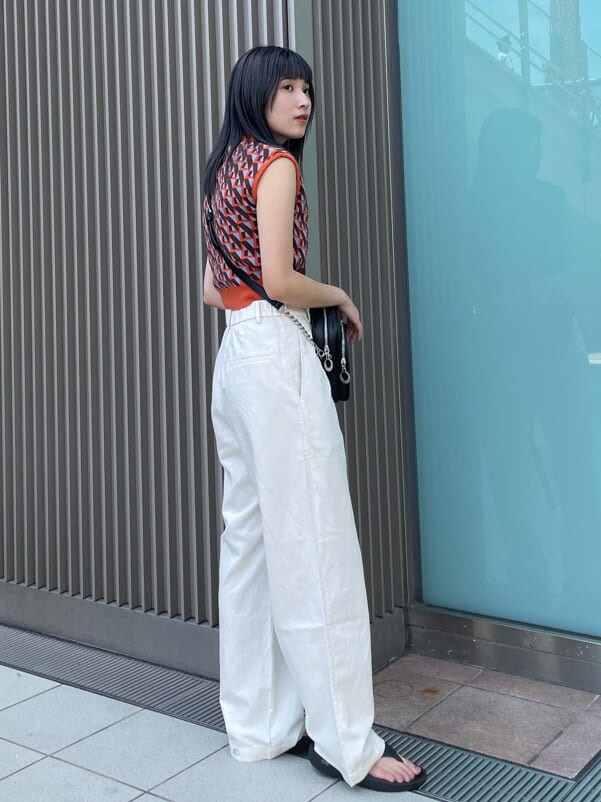 ブラック系のショルダーバッグ、オレンジ系のニット/セーターを着用したレディースの夏コーディネートの2枚目の写真