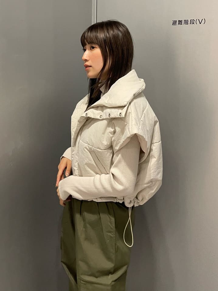 ホワイト系のダウンベスト、ブラック系のブーツ、ホワイト系のニット/セーターを着用したレディースの秋コーディネートの4枚目の写真