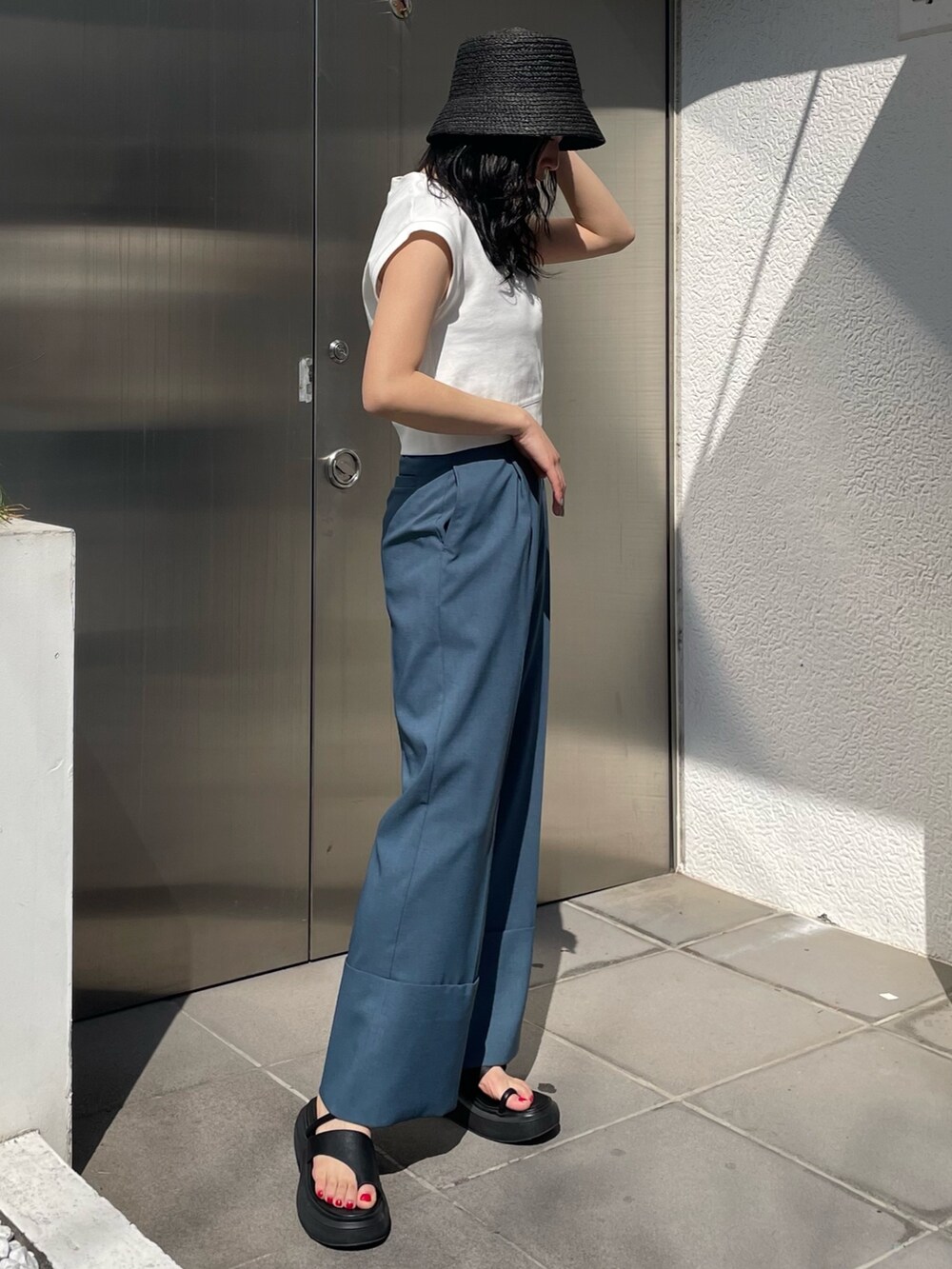 ブラック系のサンダル、ブルー系のスラックス、ホワイト系のタンクトップを着用したレディースの春コーディネートの3枚目の写真