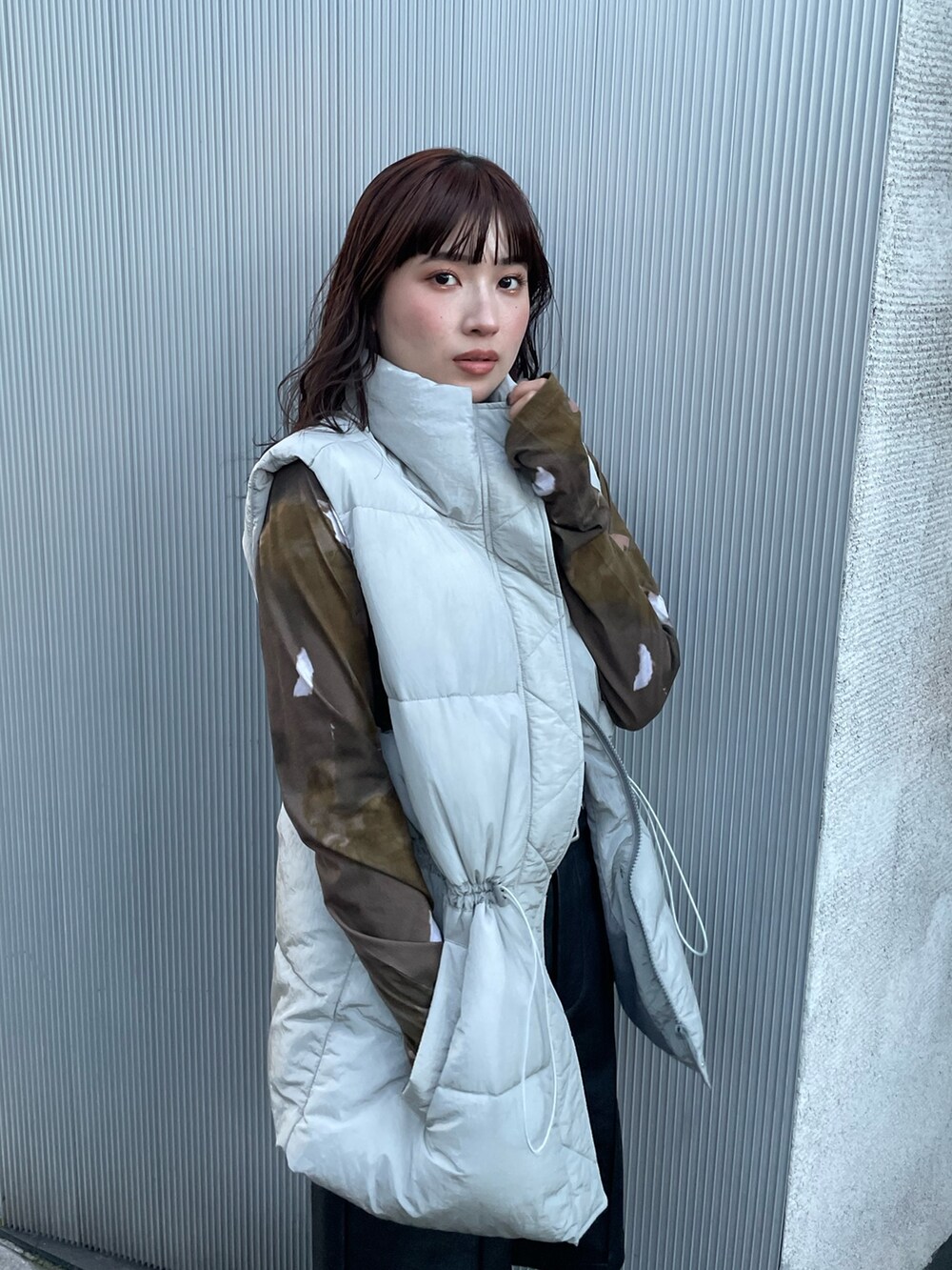 ホワイト系のTシャツ/カットソー、グレー系のダウンベスト、ブラック系のその他パンツを着用したレディースの秋コーディネートの4枚目の写真