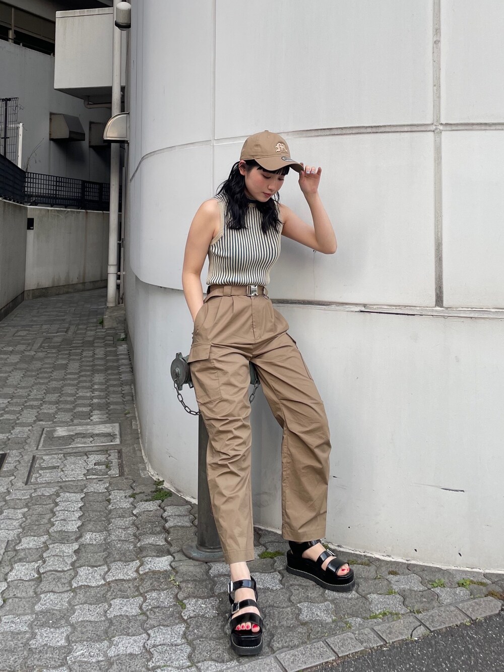 グリーン系のカーゴパンツ、ベージュ系のニット/セーター、ベージュ系のキャップを着用したレディースの春コーディネートの2枚目の写真
