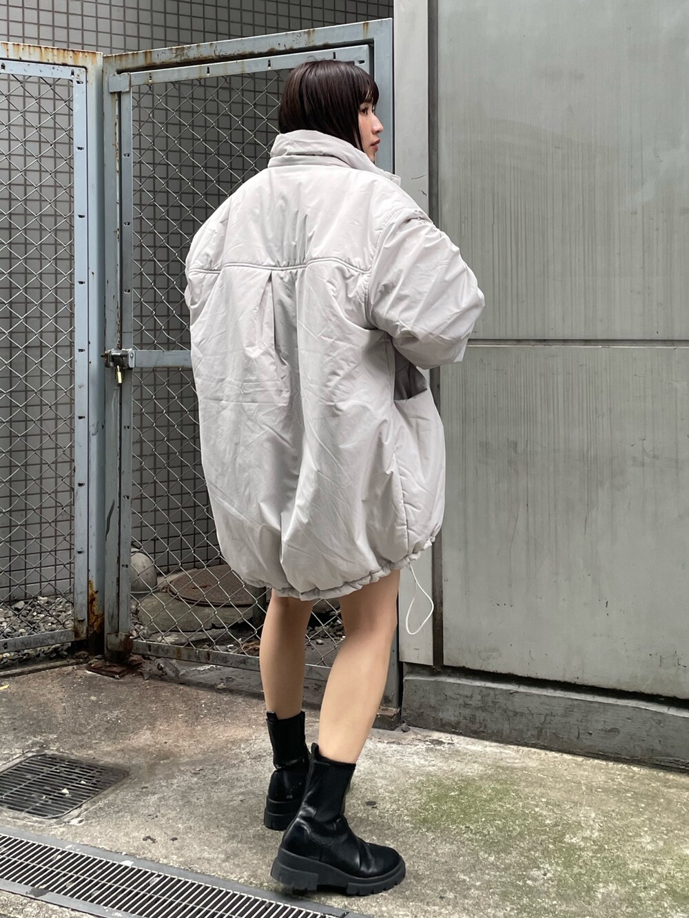 ホワイト系のブルゾン、ブラック系のワンピース、ブラック系のブーツを着用したレディースの冬コーディネートの3枚目の写真