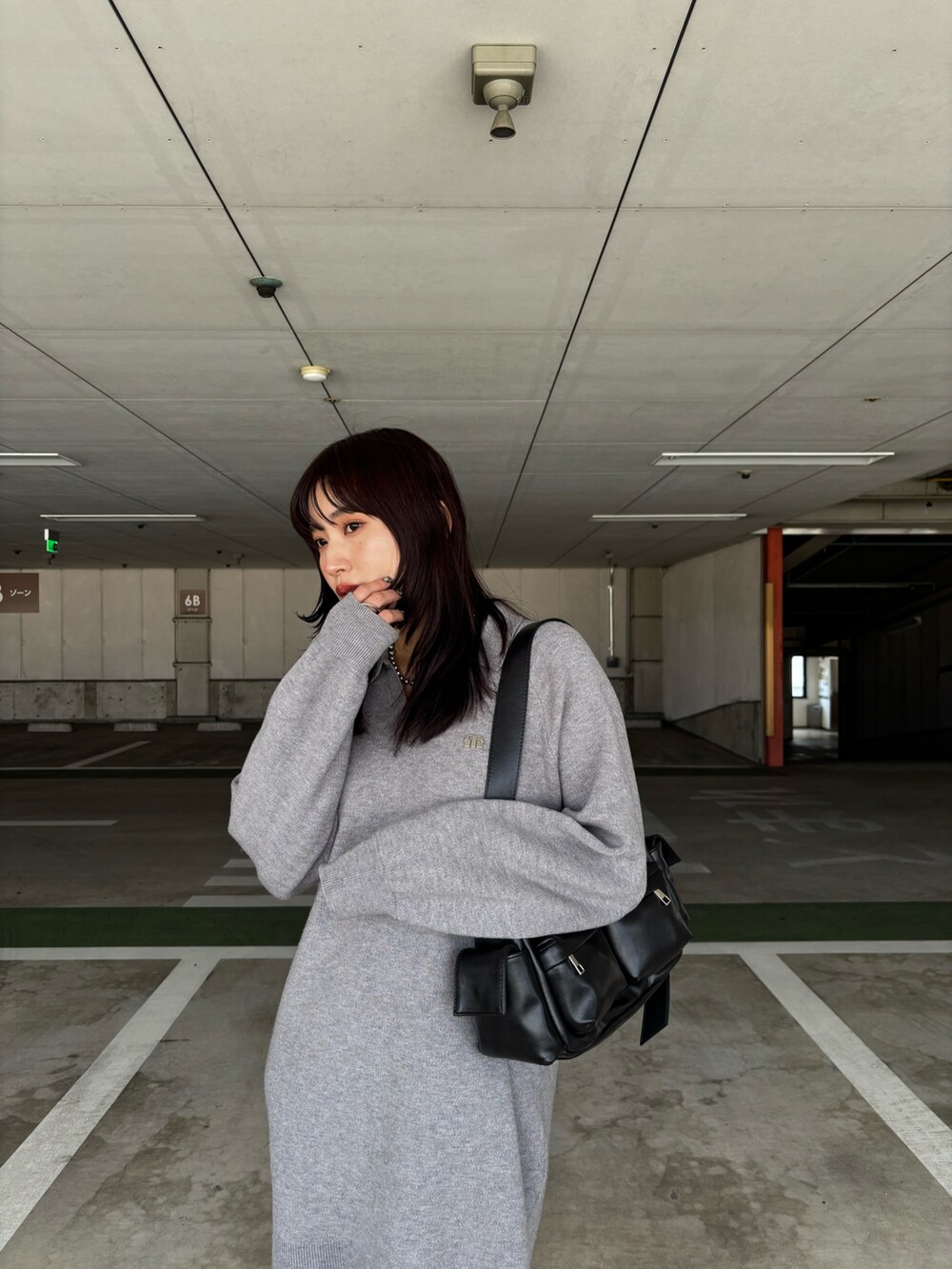 グレー系のワンピース、ブラウン系のブーツ、ブラック系のショルダーバッグを着用したレディースの冬コーディネートの4枚目の写真