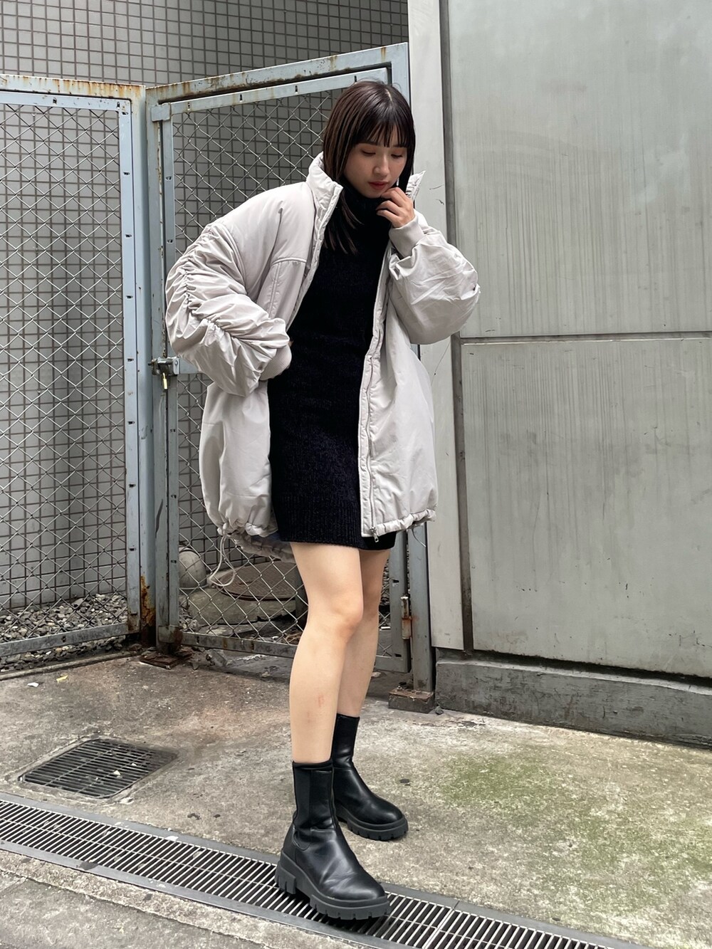ホワイト系のブルゾン、ブラック系のワンピース、ブラック系のブーツを着用したレディースの冬コーディネートの2枚目の写真