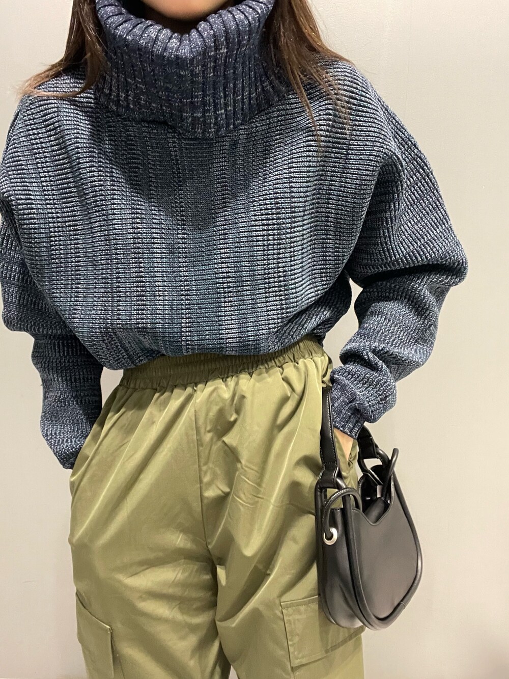 ブルー系のニット/セーター、ブラック系のハンドバッグ、ブラック系のブーツを着用したレディースの秋コーディネートの6枚目の写真