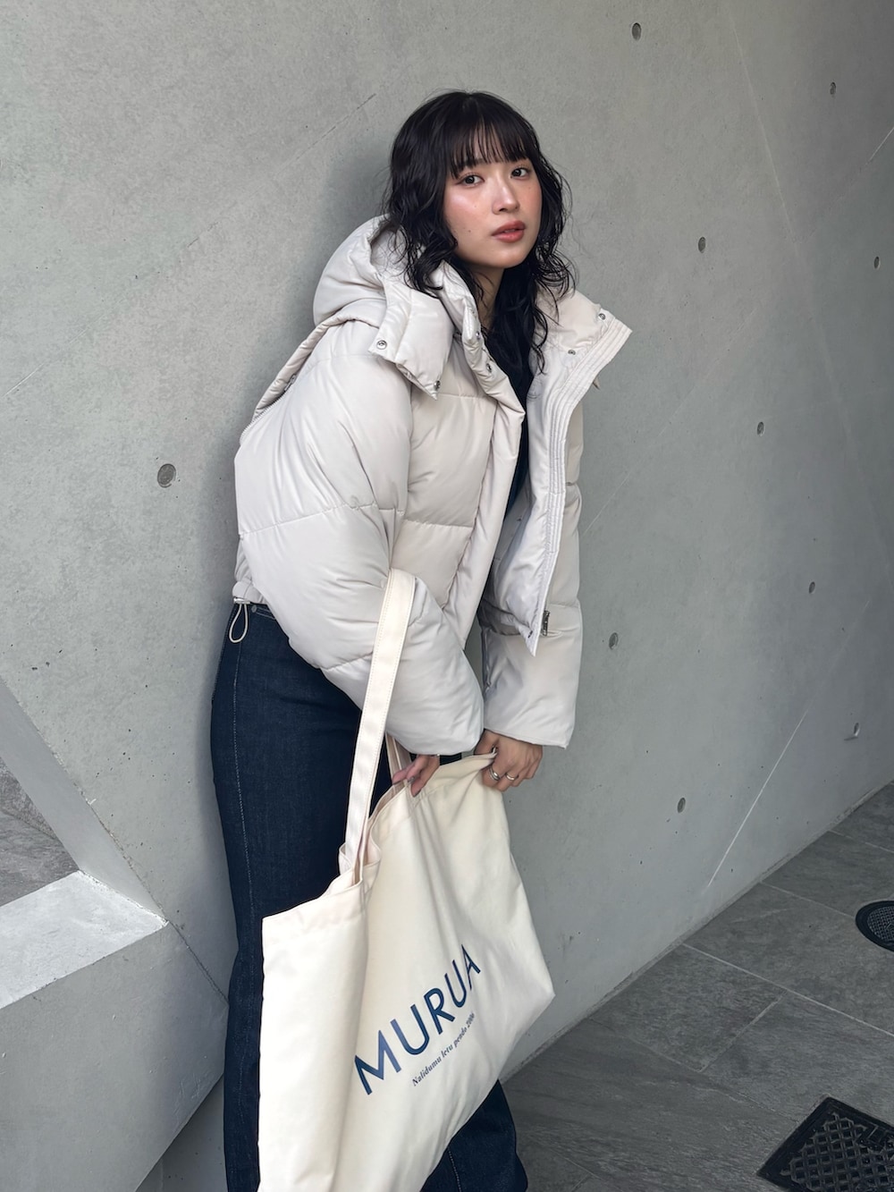 ホワイト系のブルゾン、ブラック系のニット/セーター、ブルー系のデニムパンツを着用したレディースの冬コーディネートの3枚目の写真