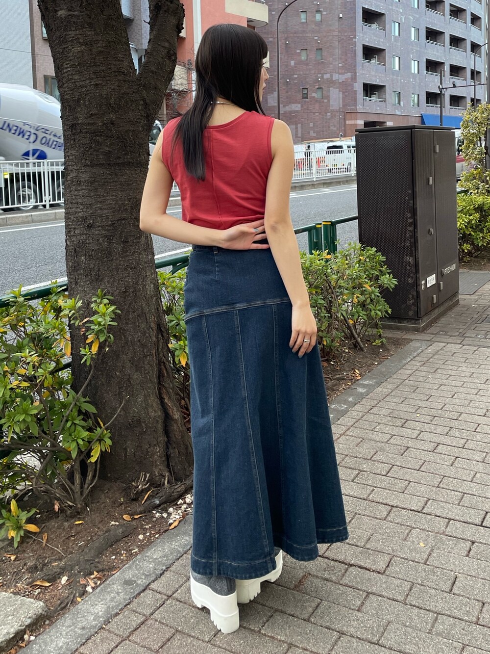 レッド系のタンクトップ、ブルー系のデニムスカートを着用したレディースの春コーディネートの2枚目の写真