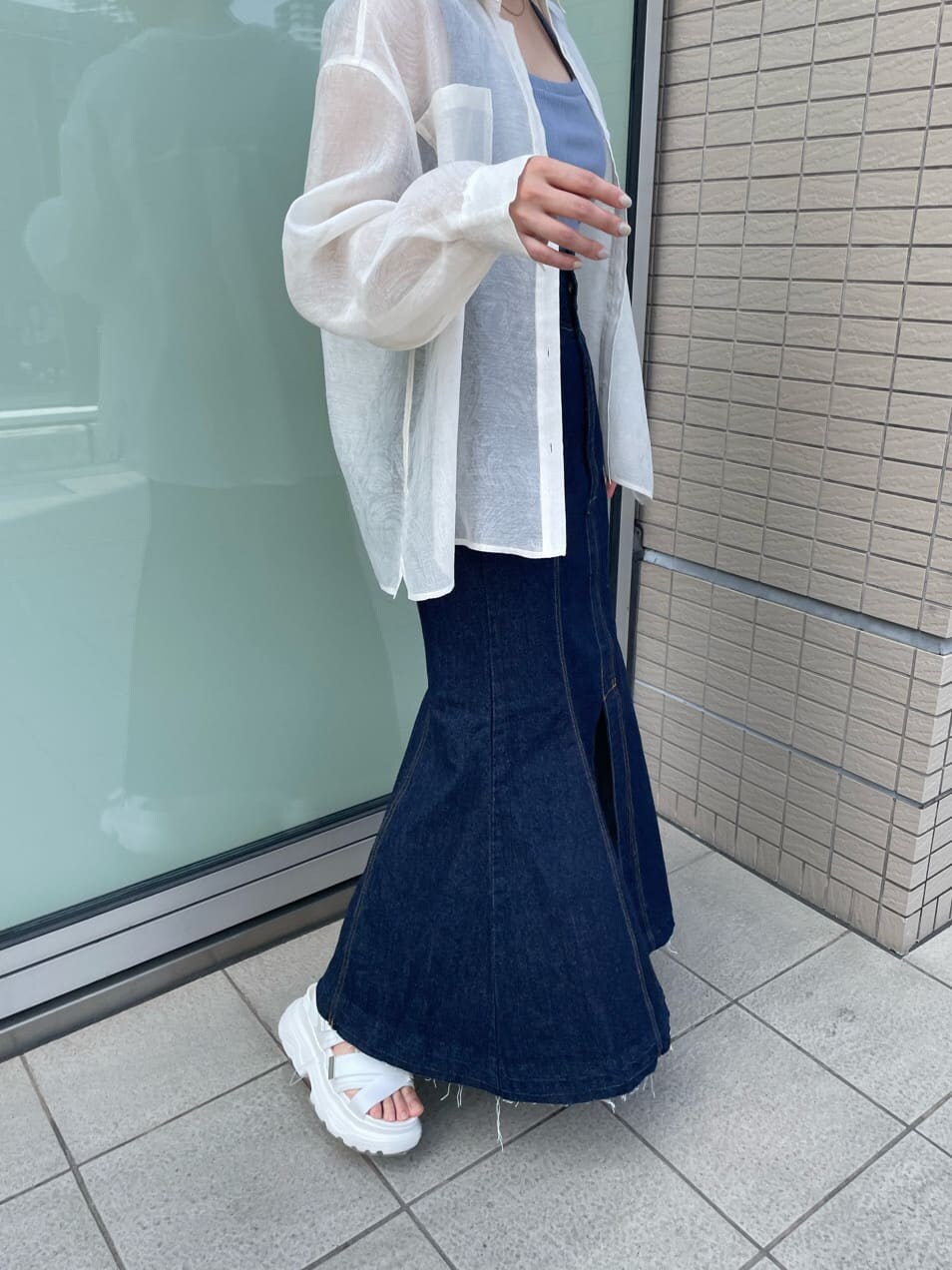 ブルー系のタンクトップ、ブルー系のデニムスカート、ホワイト系のサンダルを着用したレディースの春コーディネートの9枚目の写真