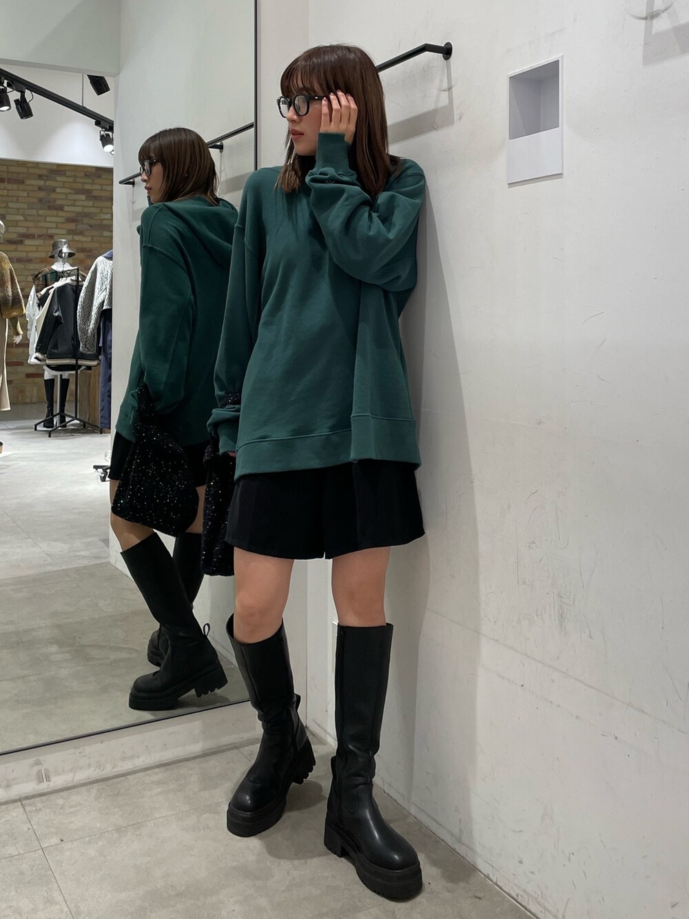 グリーン系のパーカー、ブラック系のブーツを着用したレディースの秋コーディネートの2枚目の写真
