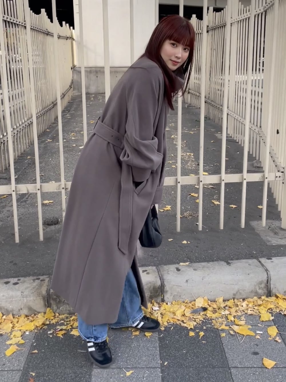 ブラウン系のステンカラーコートを着用したレディースの冬コーディネートの2枚目の写真