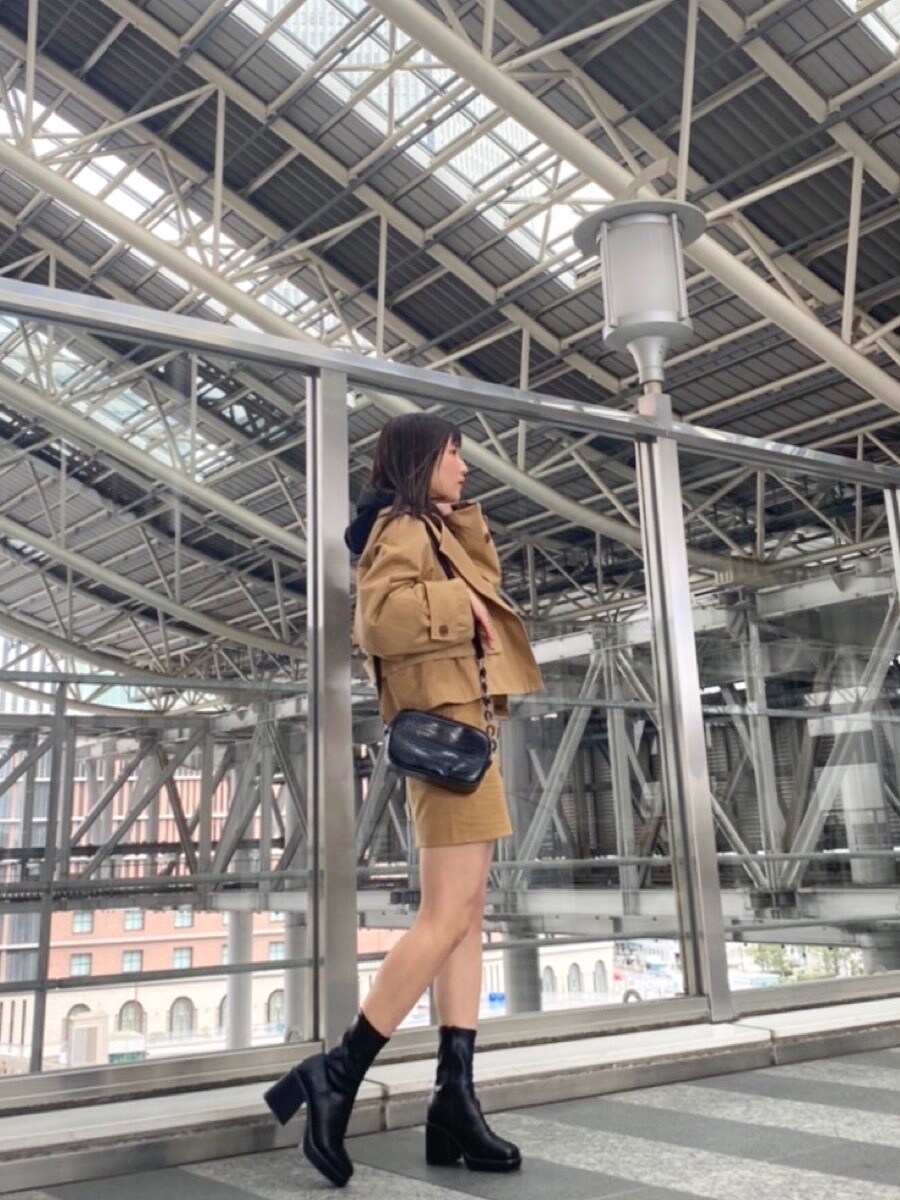 ベージュ系のトレンチコート、ベージュ系のスカート、ブラック系のブーツを着用したレディースの冬コーディネートの5枚目の写真