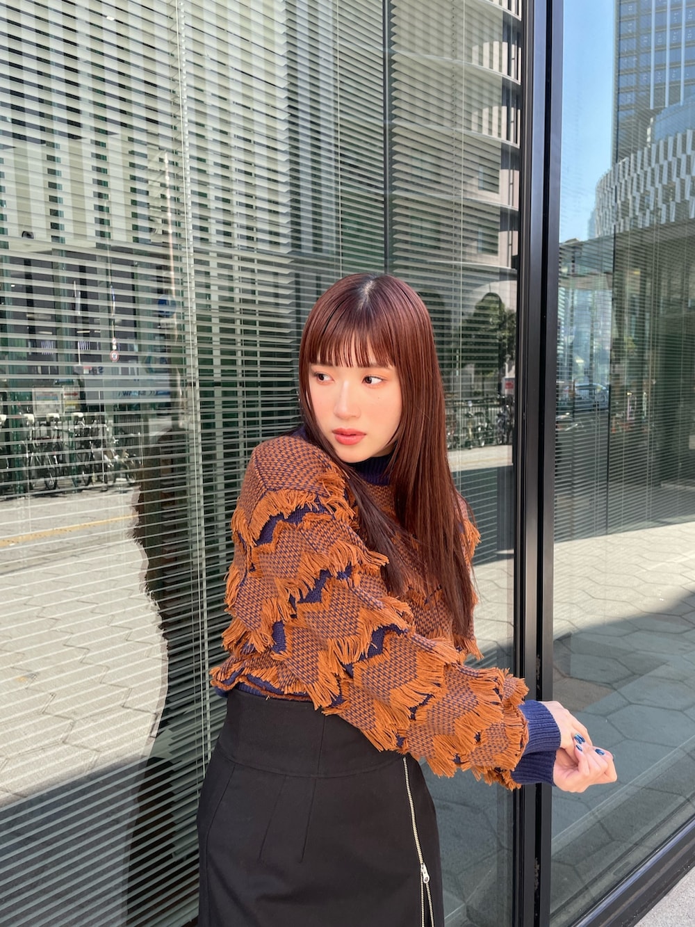 ブラック系のスカート、オレンジ系のニット/セーターを着用したレディースの秋コーディネートの3枚目の写真