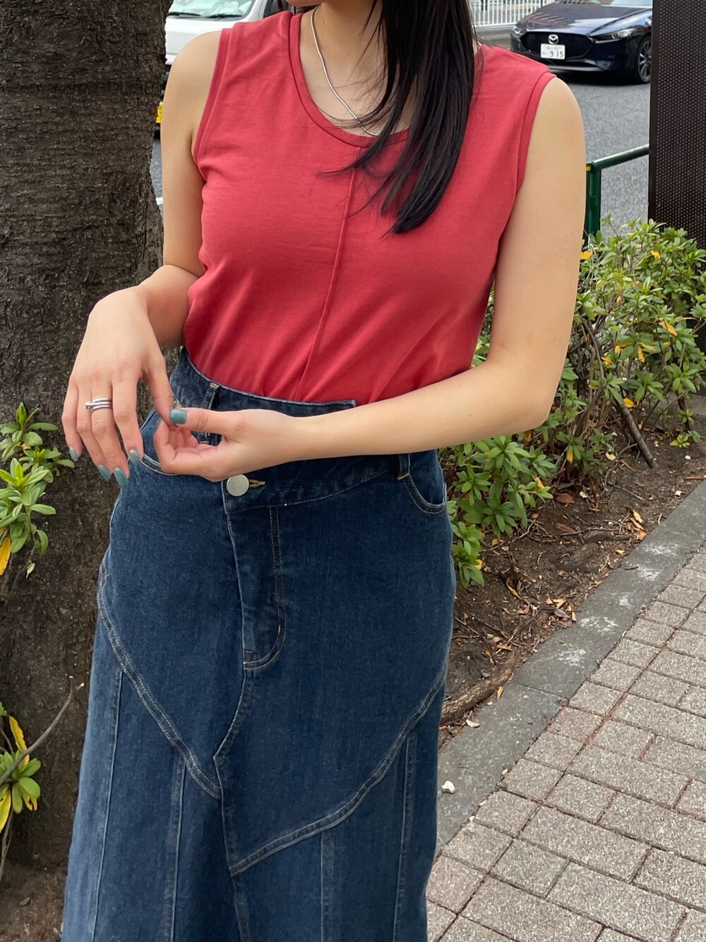 レッド系のタンクトップ、ブルー系のデニムスカートを着用したレディースの春コーディネートの3枚目の写真