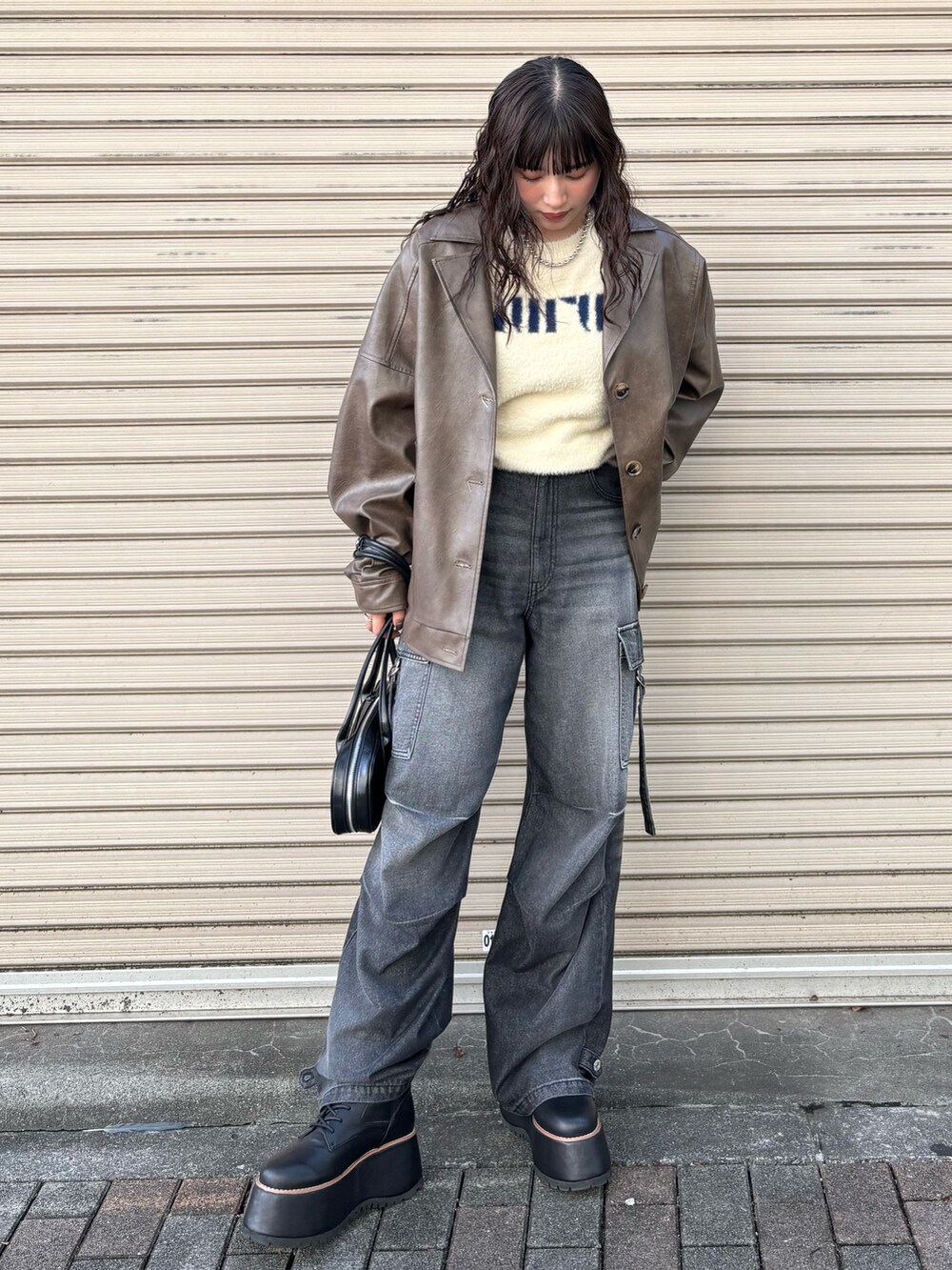 ブラウン系のブルゾン、ブラック系のデニムパンツ、ホワイト系のニット/セーターを着用したレディースの秋コーディネートの2枚目の写真