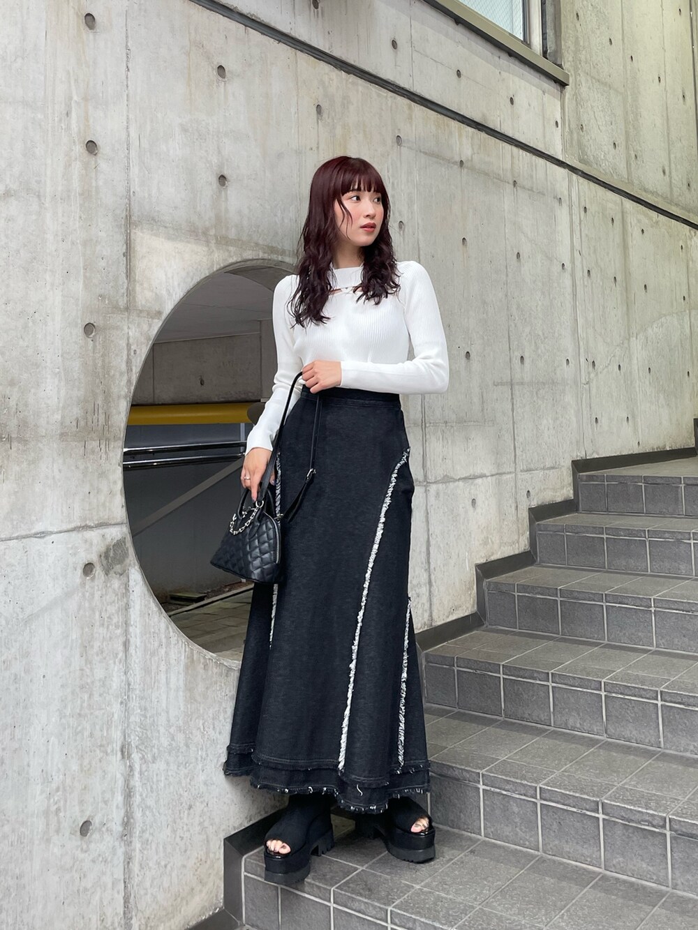 ホワイト系のニット/セーター、ブラック系のデニムスカートを着用したレディースの冬コーディネートの2枚目の写真
