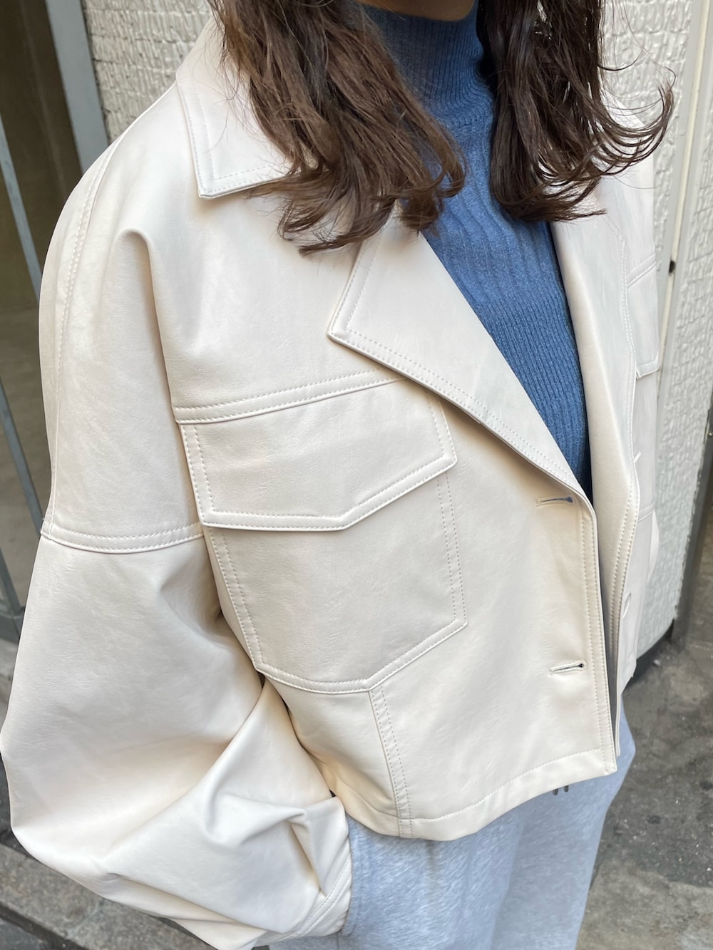 ブルー系のニット/セーター、ホワイト系のライダースジャケットを着用したレディースの冬コーディネートの6枚目の写真