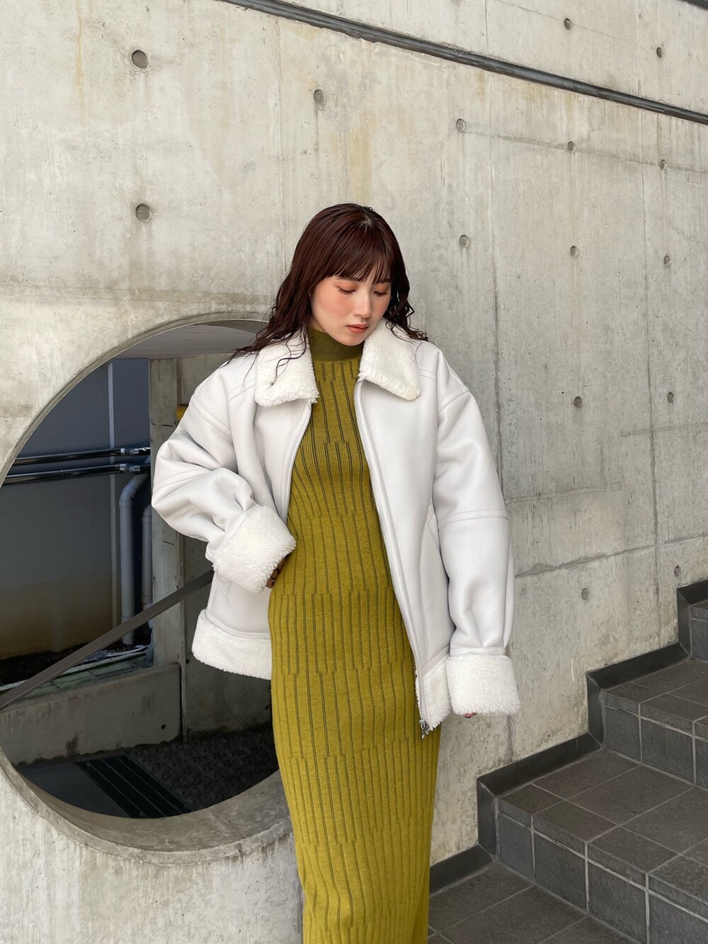 グレー系のムートンコート、イエロー系のワンピースを着用したレディースの秋コーディネートの2枚目の写真
