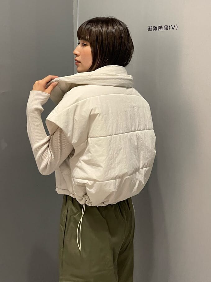 ホワイト系のダウンベスト、ブラック系のブーツ、ホワイト系のニット/セーターを着用したレディースの秋コーディネートの6枚目の写真