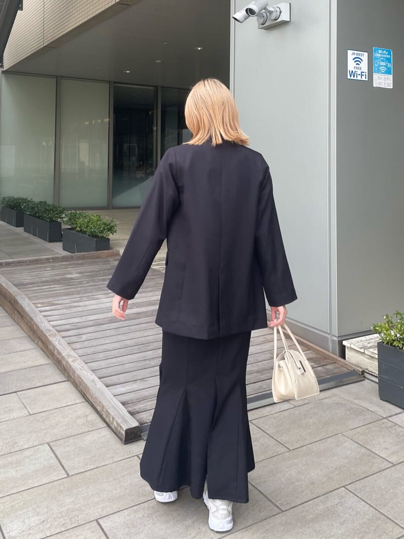 ブラック系のテーラードジャケット、ホワイト系のハンドバッグ、ブラック系のスカートを着用したレディースの春コーディネートの4枚目の写真