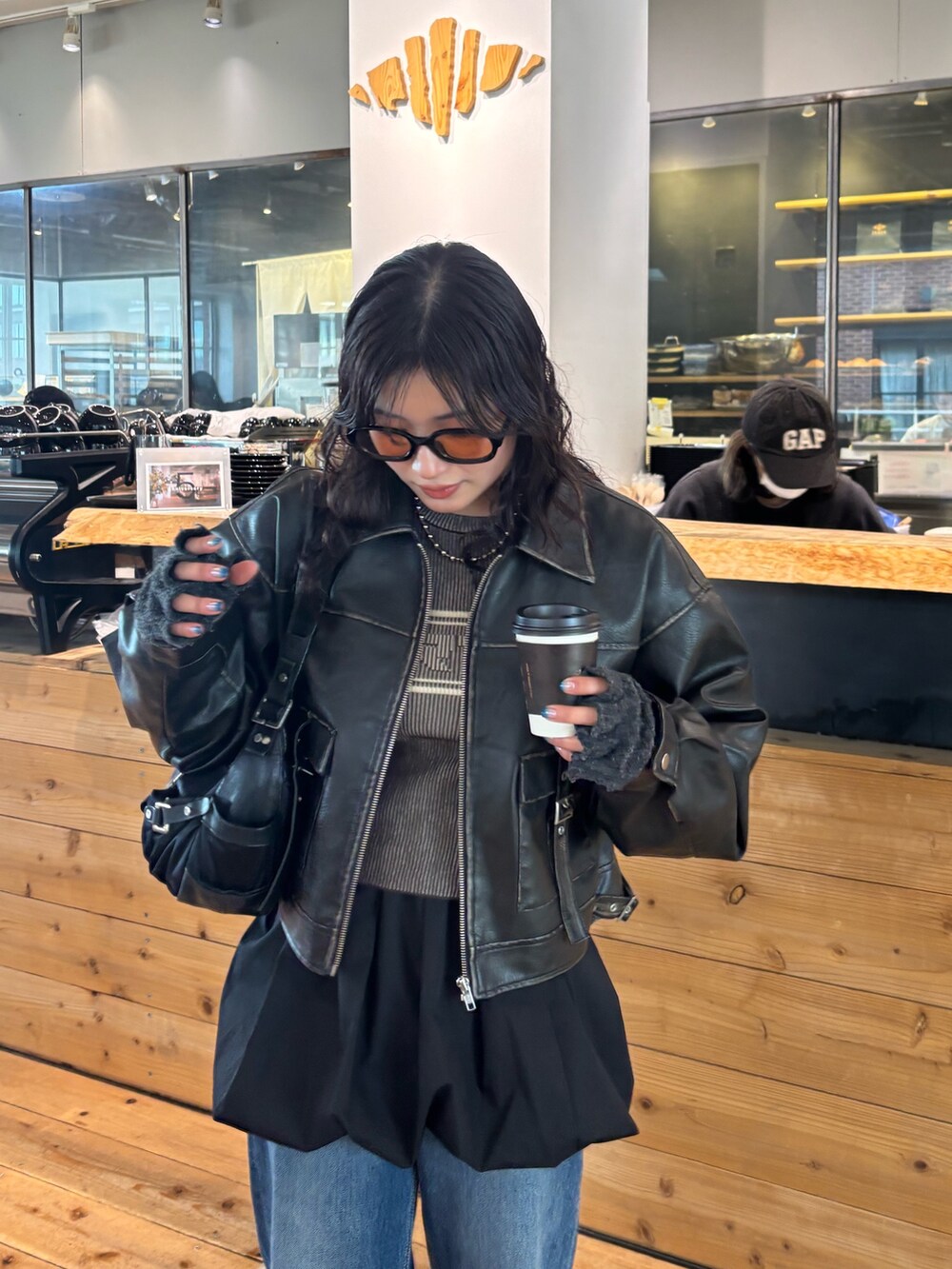 ブラウン系のニット/セーター、ブラック系のブルゾンを着用したレディースの春コーディネートの2枚目の写真