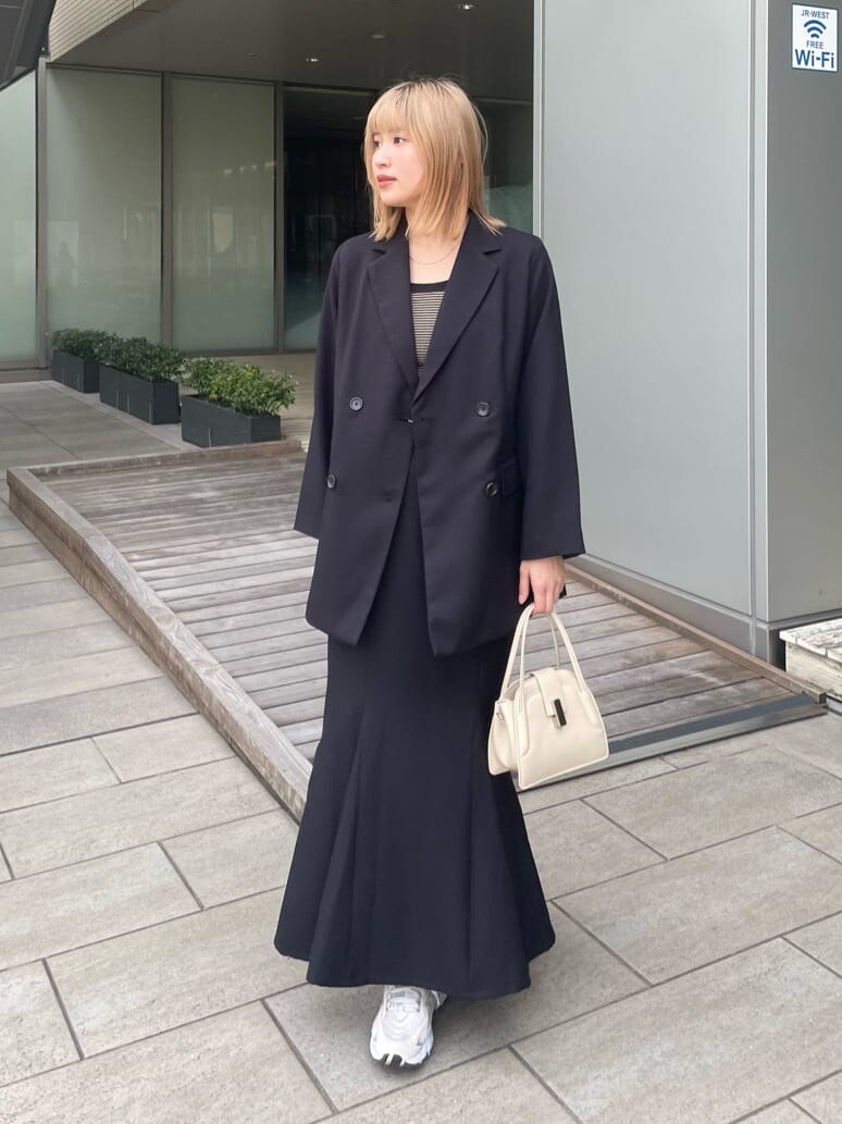 ブラック系のテーラードジャケット、ホワイト系のハンドバッグ、ブラック系のスカートを着用したレディースの春コーディネートの3枚目の写真