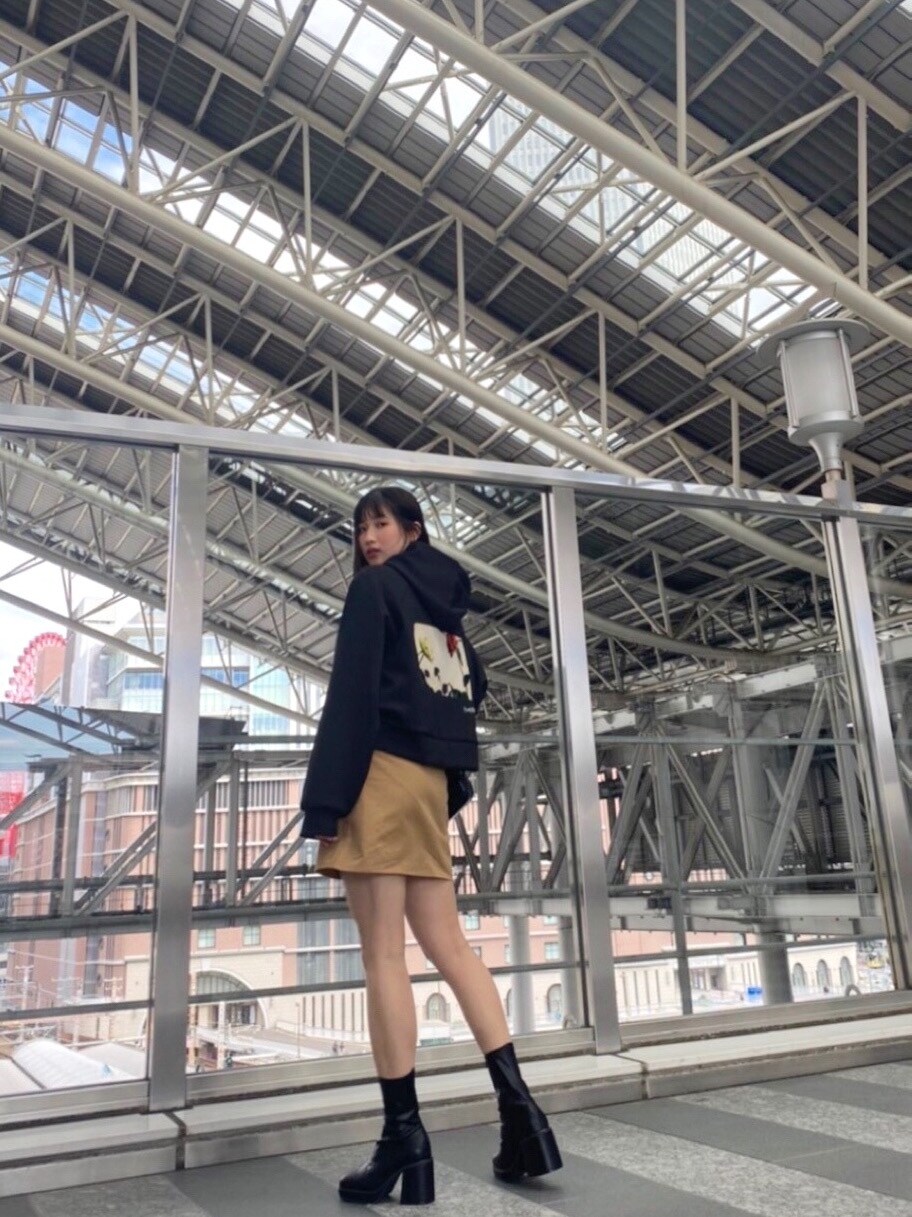 ベージュ系のトレンチコート、ベージュ系のスカート、ブラック系のブーツを着用したレディースの冬コーディネートの3枚目の写真