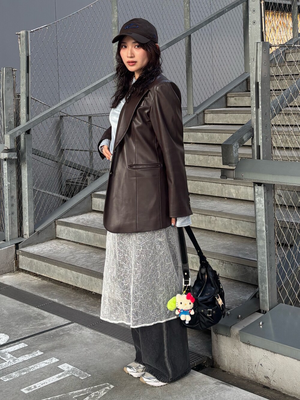 ブラック系のデニムパンツ、ホワイト系のストール/ショール、ブラウン系のキャップを着用したレディースの春コーディネートの2枚目の写真