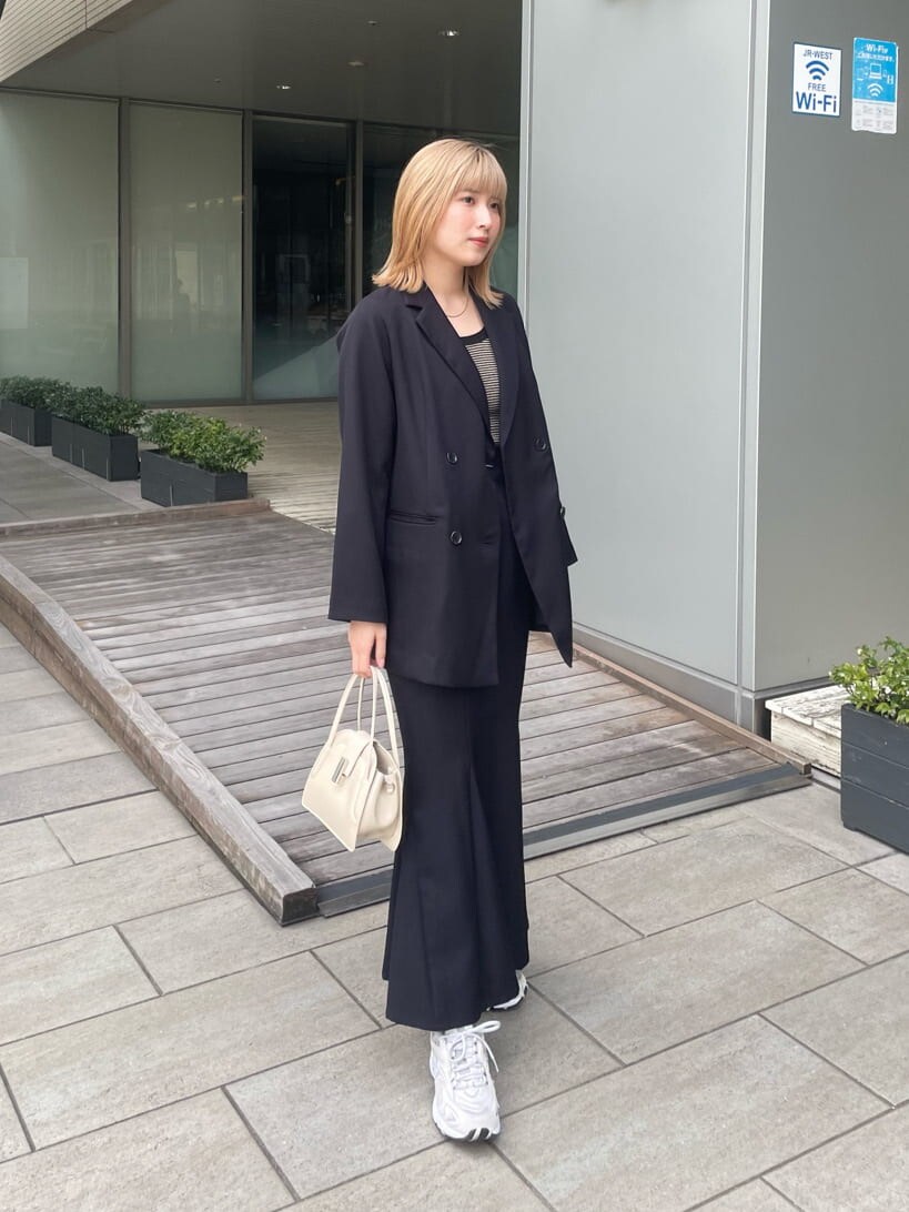 ブラック系のテーラードジャケット、ホワイト系のハンドバッグ、ブラック系のスカートを着用したレディースの春コーディネートの2枚目の写真