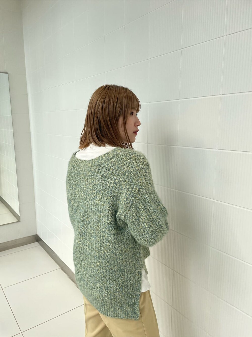 グリーン系のニット/セーター、イエロー系のスラックスを着用したレディースの冬コーディネートの6枚目の写真