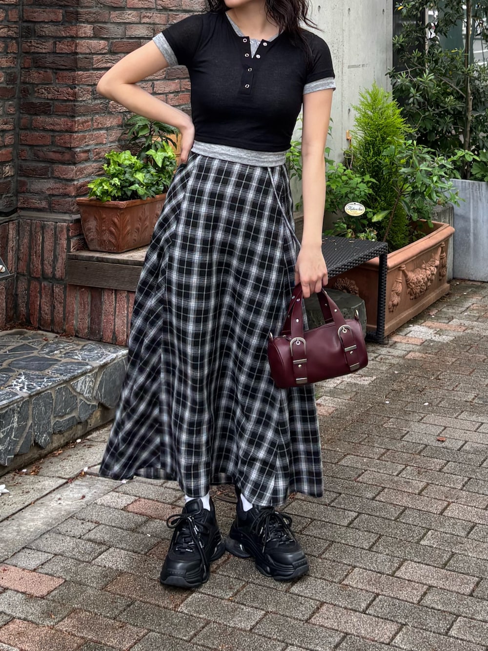 ブラック系のTシャツ/カットソー、ブラック系のスカート、ブラック系のスニーカーを着用したレディースの春コーディネートの2枚目の写真