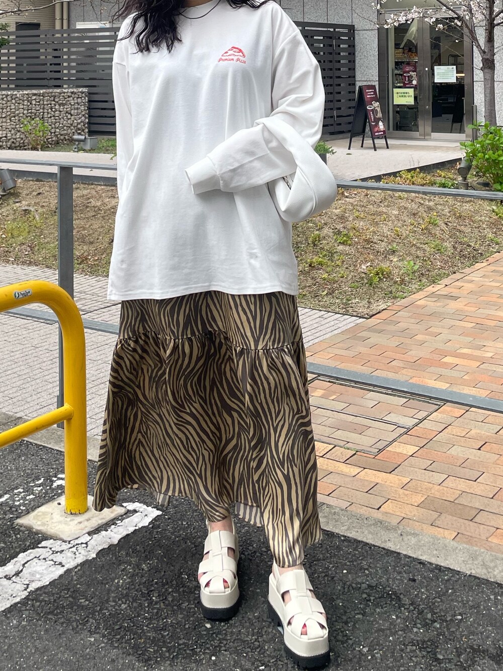 ホワイト系のTシャツ/カットソー、ベージュ系のスカート、ホワイト系のハンドバッグを着用したレディースの春コーディネートの2枚目の写真