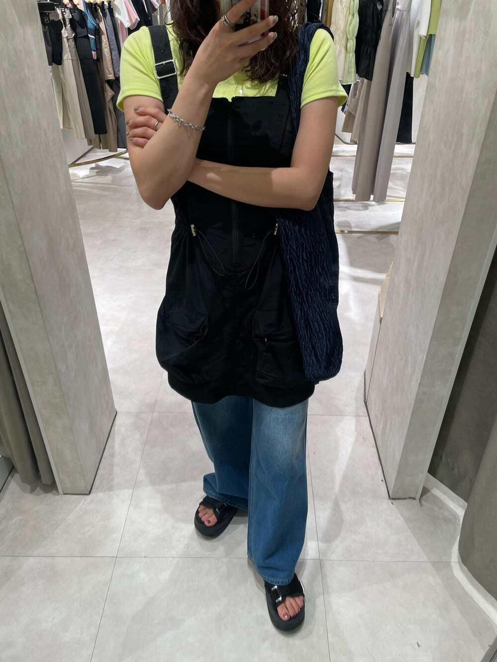 ブラック系のワンピース、ブルー系のデニムパンツ、ブラック系のサンダルを着用したレディースの春コーディネートの2枚目の写真