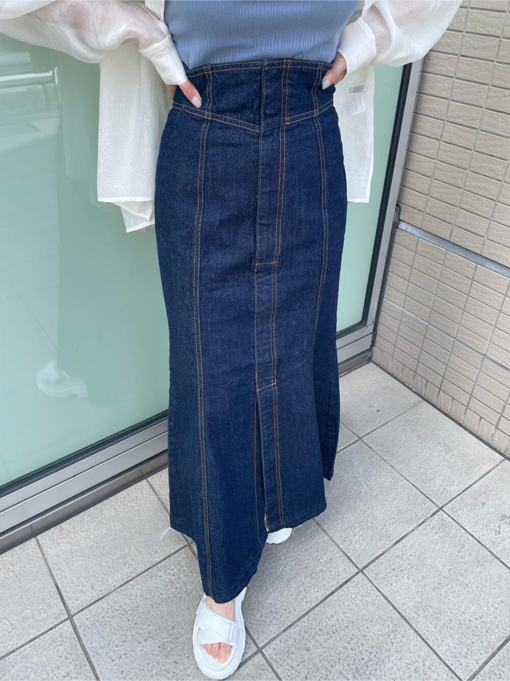 ブルー系のタンクトップ、ブルー系のデニムスカート、ホワイト系のサンダルを着用したレディースの春コーディネートの8枚目の写真