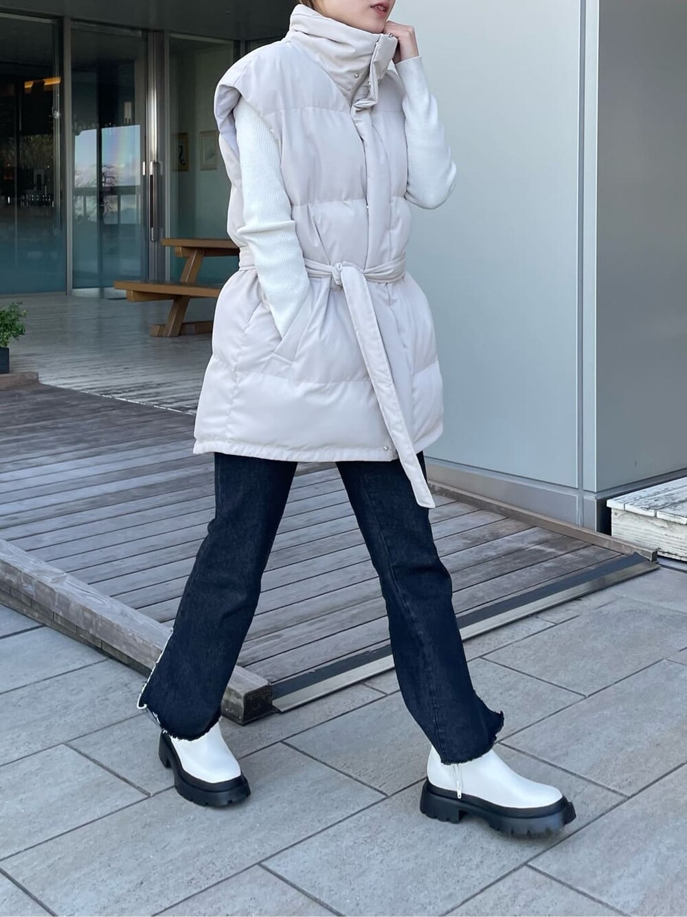 ホワイト系のダウンベスト、ブラック系のデニムパンツ、ホワイト系のニット/セーターを着用したレディースの冬コーディネートの2枚目の写真