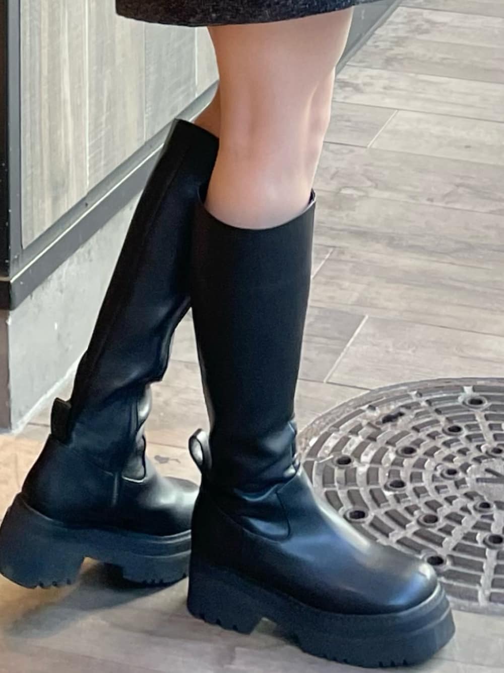 ブラック系のワンピース、ブラック系のブーツ、ブラック系のショルダーバッグを着用したレディースの冬コーディネートの7枚目の写真